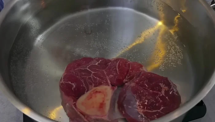 Rinderbeinscheiben und Knochen in einen Topf geben, mit kaltem Wasser bedecken.