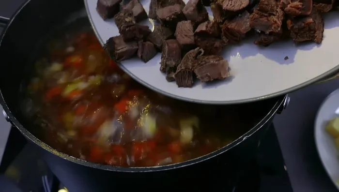 Fleischklößchen und das Fleisch von den Beinscheiben in die Suppe geben. Aufkochen.