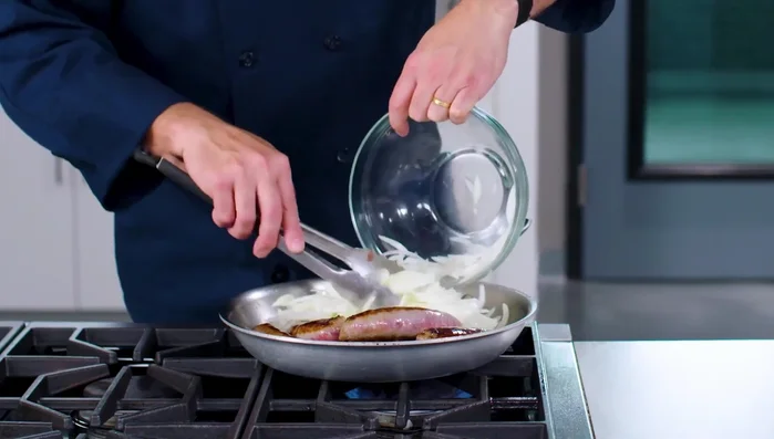 Die Würstchen darauflegen und eine halbe Tasse Wasser hinzufügen. Die Pfanne abdecken und die Würstchen braten, bis sie eine Temperatur zwischen 160 und 165°C erreicht haben und die Zwiebeln weich sind (ca. 10 Minuten).