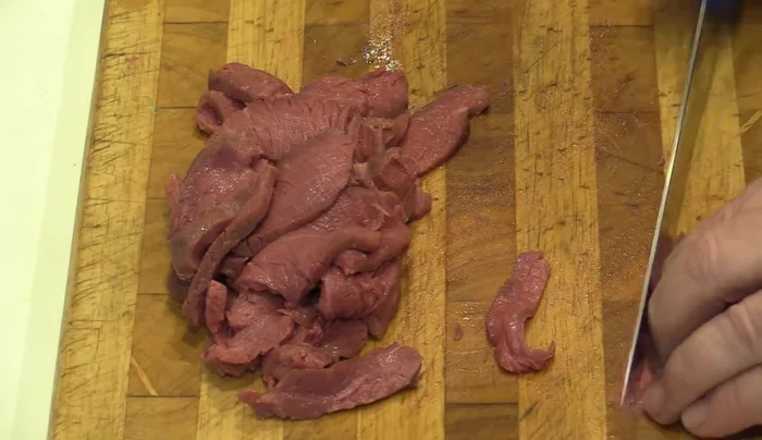 Die Rindfleischscheiben in dünne Streifen schneiden.