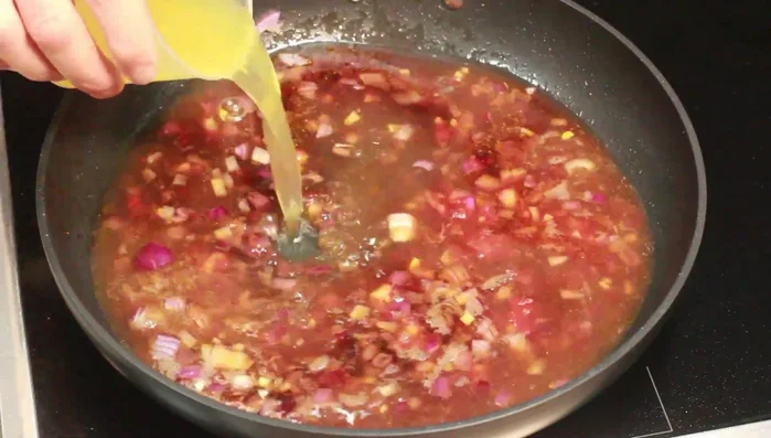 Apfelsaft und Brühe hinzufügen, verrühren und kurz aufkochen. Hitze reduzieren und 10 Minuten köcheln lassen.