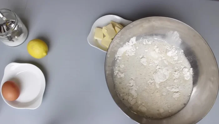 Milch-Hefe-Zucker-Mischung zum Mehl geben. Zitronenabrieb und Vanillezucker hinzufügen.