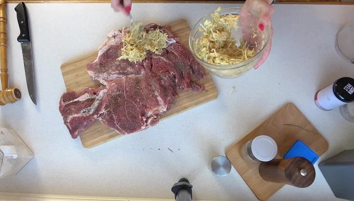 Füllung auf dem Braten verteilen und aufrollen. Mit Küchengarn festbinden.