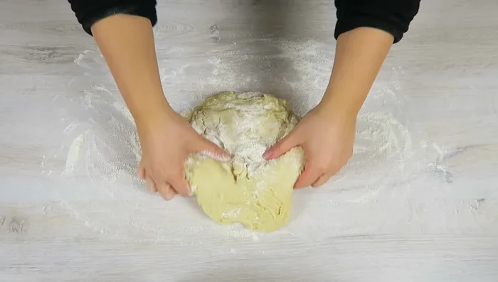 Teig auf einer bemehlten Fläche auf die Größe des Backblechs ausrollen und auf ein mit Backpapier ausgelegtes Backblech legen. Mit den Händen die Ränder ausformen.