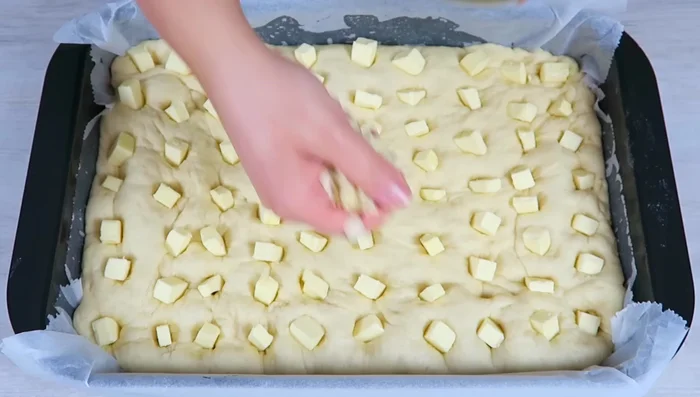 Gehobelte Mandeln und Zucker gleichmäßig über den Kuchen verteilen.