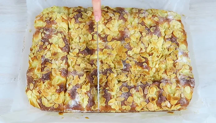 Kuchen abkühlen lassen, aus dem Backblech nehmen und in Stücke schneiden.