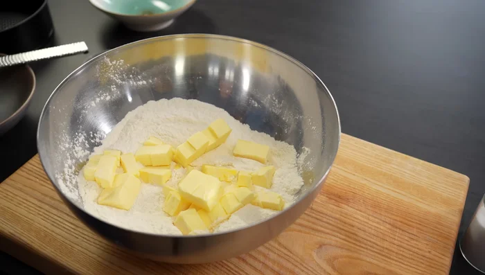 Kalte Butter in die trockenen Zutaten einreiben. Ei hinzufügen und zu einem krümeligen Teig verarbeiten. (305.28)