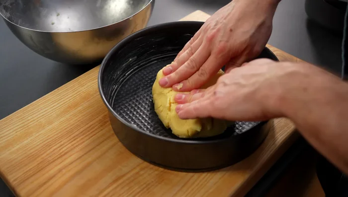 Restlichen Teig in eine gefettete Backform (26cm) drücken und den Rand hochziehen. 10 Minuten kühl stellen. (389.639)