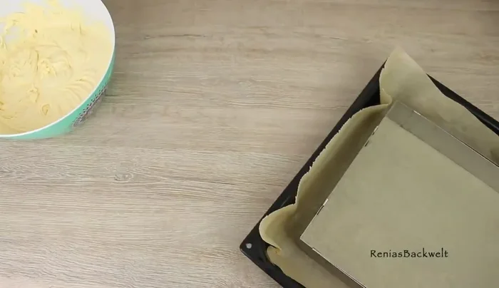 Teig in einen mit Backpapier ausgelegten Backrahmen (29x23cm) geben und gleichmäßig verstreichen.