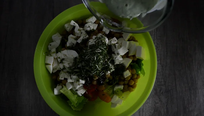 Einen Teil des Avocado-Dressings zum Salat geben und vermischen.