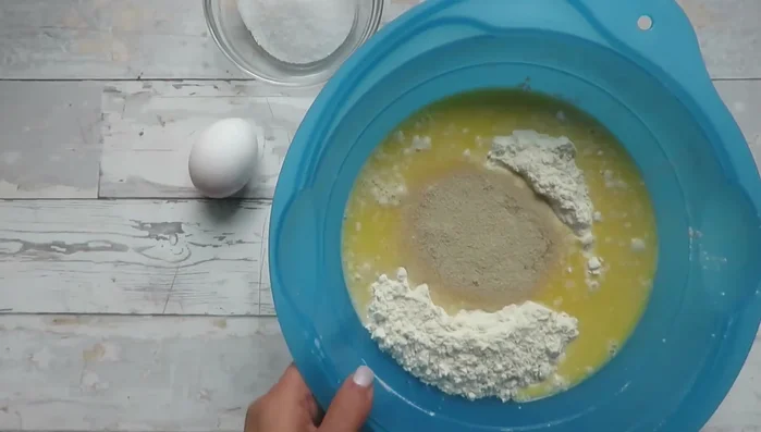 Alle Zutaten für den Hefeteig (außer der Hefe) zum Mehl geben und zuerst mit einer Gabel vermischen, dann mit den Händen kneten (ca. 1 Minute).