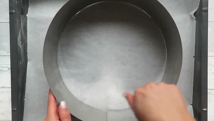 Den Tortenring mit Backpapier auslegen und einfetten. Den Teig darin verteilen und 30 Minuten ruhen lassen.