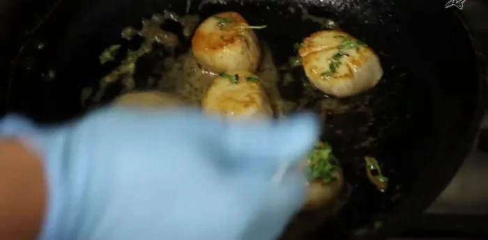 Jakobsmuscheln mit Salz, Pfeffer, brauner Butter und Thymian abschmecken. Mit grobem Meersalz bestreuen.