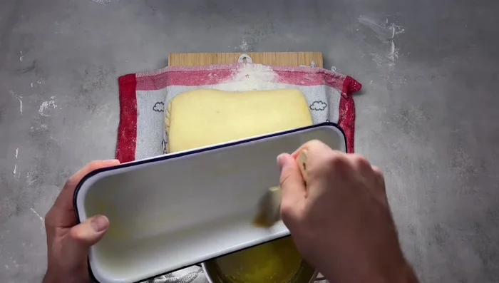 Den Teig mit der Füllung aufrollen und in eine eingefettete Kastenform legen.