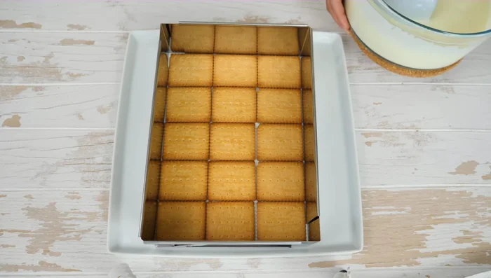 Butterkekse auf einer Servierplatte mit Tortenrahmen auslegen.