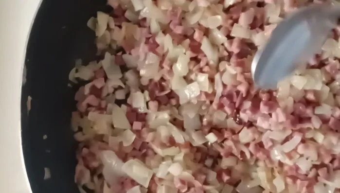 Zwiebeln und Schinken auf die Käse-Quark-Masse legen.