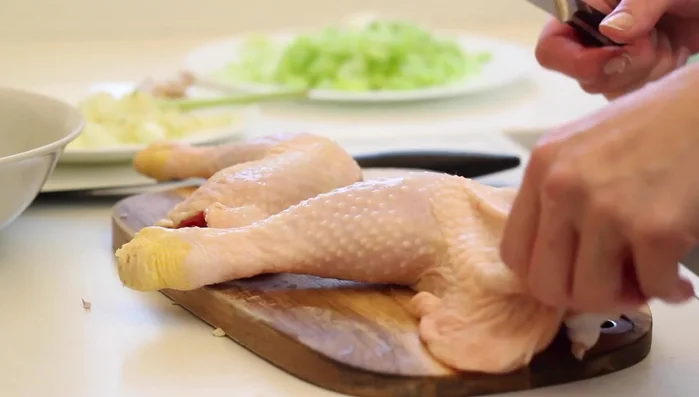 Haut und Knochen von den Hähnchenschenkeln entfernen und Fleisch in mundgerechte Stücke schneiden.