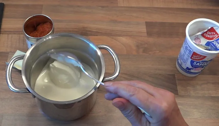 Safransauce zubereiten: Sahne und Safran in einem Topf verrühren, mit Piment und Pfeffer abschmecken.