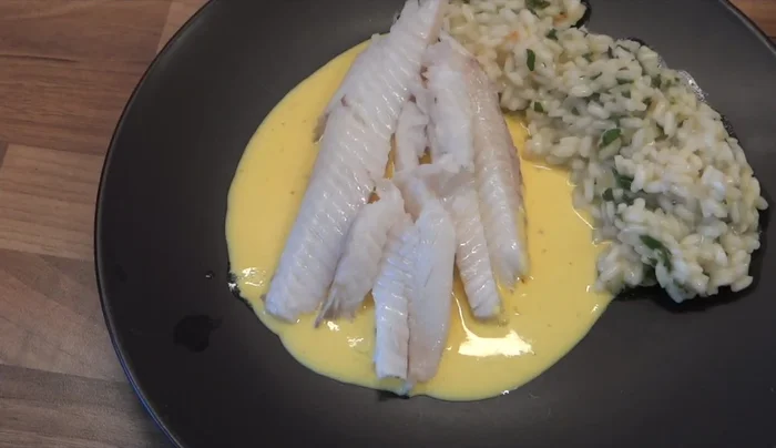 Zitronenreis und Safransauce neben dem Heilbutt anrichten. Mit Petersilie garnieren. Mit Salz und Pfeffer abschmecken.