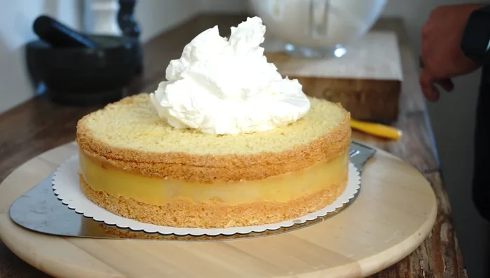 Die Hälfte der geschlagenen Sahne auf die Torte streichen.