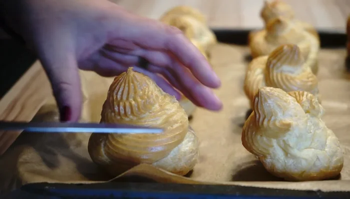 Die Windbeutel mit einem Messer halbieren und mit der Sahne füllen. (306.809)