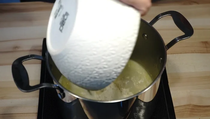 Sobald die Butter geschmolzen ist und die Flüssigkeit kocht, das Mehl hinzufügen und sofort kräftig verrühren, bis ein Teig entsteht. (80.68)