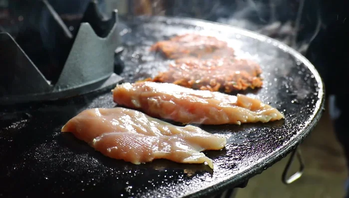 Hähnchenfleisch auf die Grillplatte legen und mit Öl beträufeln.