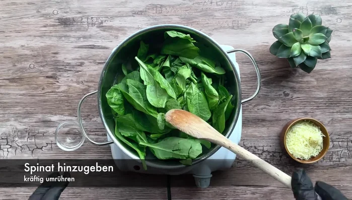 Gewaschenen Blattspinat hinzufügen und kräftig umrühren. Mehrmals wiederholen.