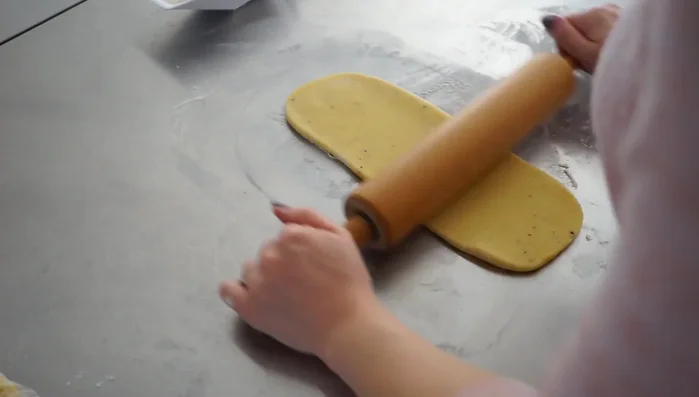 Rand formen: Die Teigreste zu einem Strang rollen und daraus einen Rand formen. Den Rand in den Tortenring legen.