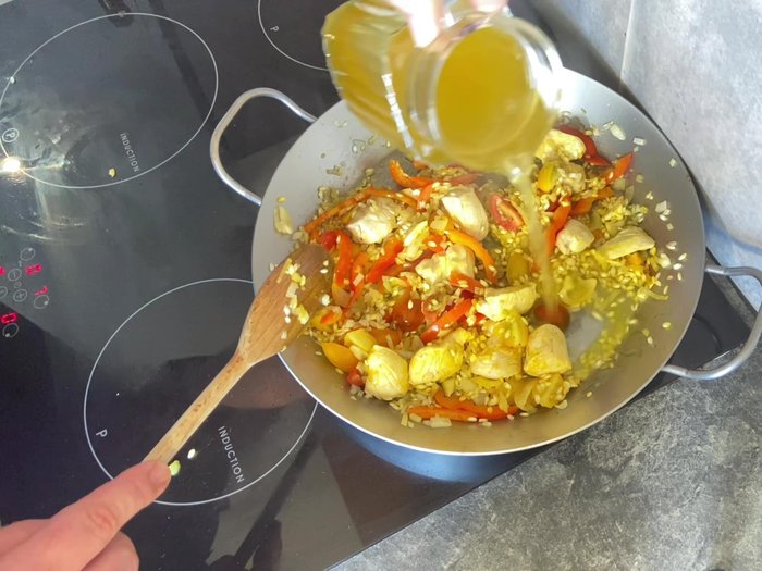 Gemüsebrühe hinzufügen (ca. 300g pro 100g Reis). Leicht köcheln lassen, bis der Reis fast die gesamte Flüssigkeit aufgenommen hat.