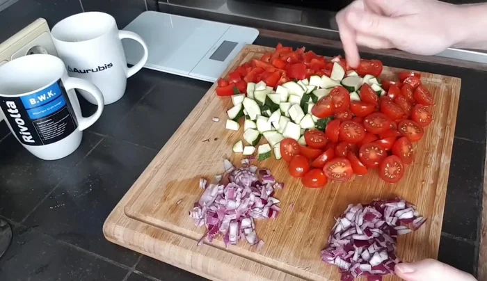 Paprika, Zucchini und Cocktailtomaten klein schneiden. Zwiebeln würfeln.