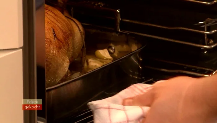Gans auf kaltes Gitter legen (10-15 Min. ruhen lassen). Dann auf Gitter mit Backblech darunter schieben. Oberhitze auf 190°C erhöhen, um die Haut knusprig zu braten.