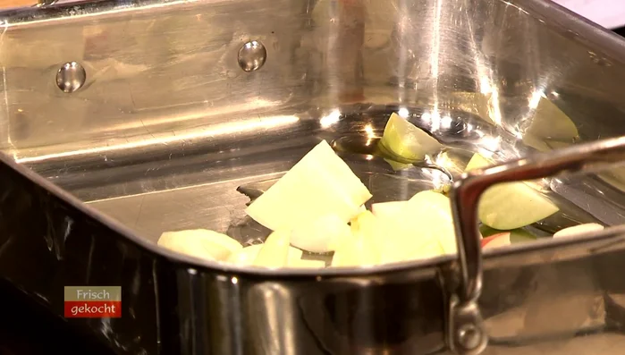 Restliche Äpfel und Zwiebeln in Gänsefett/Butter anbraten. Abgetrennte Gansenteile zugeben und mitbraten.