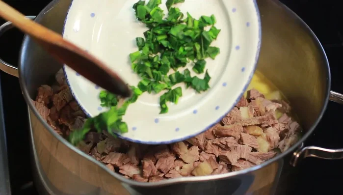 Gekochtes Rindfleisch hinzufügen, gehackte Kohlrabi Blätter unterrühren. (147.3)