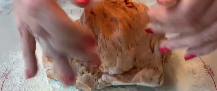 Backmatte mit Backpapier auslegen und die Teigwurst darauf legen.