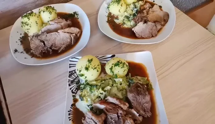 Schweinebraten, Klöße, Wirsing und Petersilie anrichten.