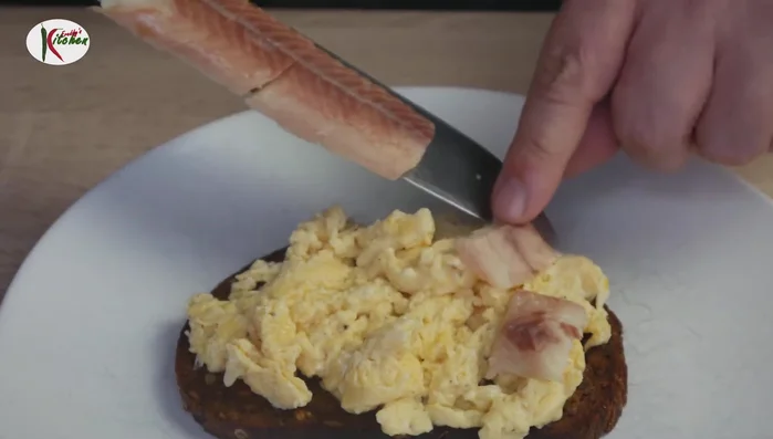 Geräucherten Aal auf dem Rührei verteilen.