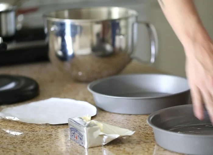 Zwei Kuchenformen vorbereiten: eine gut einfetten und ein Stück Backpapier auf den Boden legen, ebenfalls einfetten. Die kleinere Form in die größere geben.