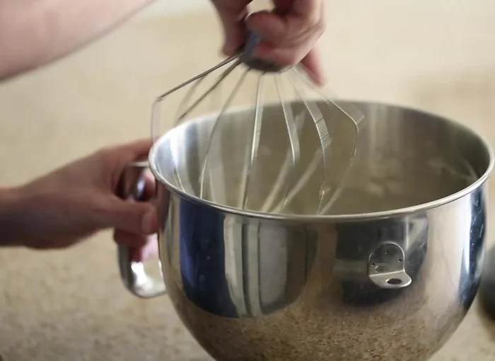 Den Mixer ausschalten und das gesiebte Kuchenmehl langsam mit einem Schneebesen oder Schneebesenaufsatz unterheben, vorsichtig um ein Zusammenfallen zu vermeiden.