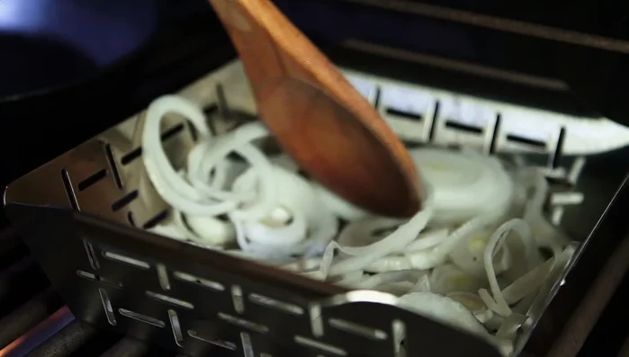 Zwiebeln im Grillkorb kurz angrillen und mit Zucker bestreuen.