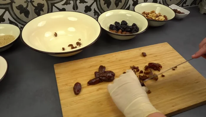 Trockenfrüchte (Datteln, Feigen, Pflaumen) in kleine Stücke schneiden und in eine Schüssel geben.