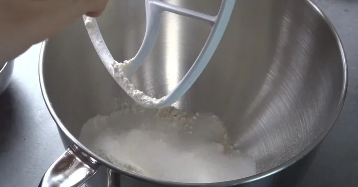 Mürbeteig zubereiten: Mehl, Zucker, Ei, kalte Butter und Zitronenabrieb in einer Schüssel verrühren.