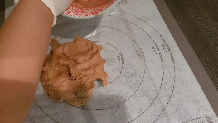 Teig auf einer mit Backpapier belegten Fläche ausrollen. Der Teig ist weich aufgrund der geschmolzenen Butter.