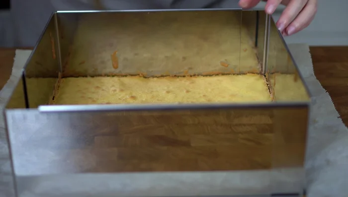 Hellen Boden aus der Backform lösen und in zwei Hälften schneiden. Untere Hälfte in die Form zurückgeben.