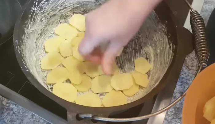 Kartoffelscheiben als erste Schicht in den Topf geben, salzen und pfeffern.