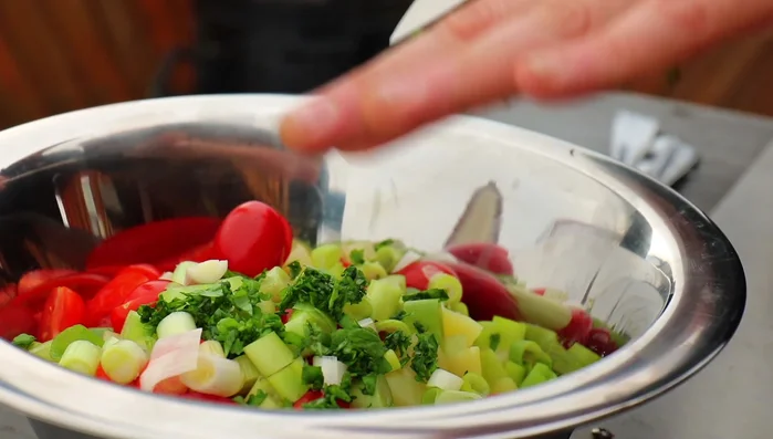 Basilikum klein hacken und zu den Tomaten, Kartoffeln und Frühlingszwiebeln hinzufügen.