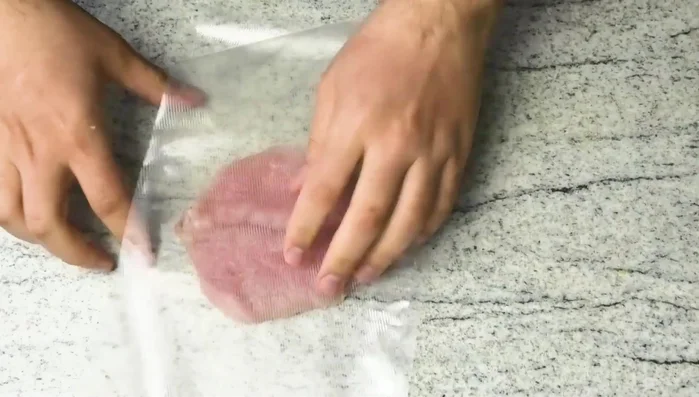 Schweinelachse dünn klopfen (siehe eingeblendetes Video für Schnitzelschnitt).