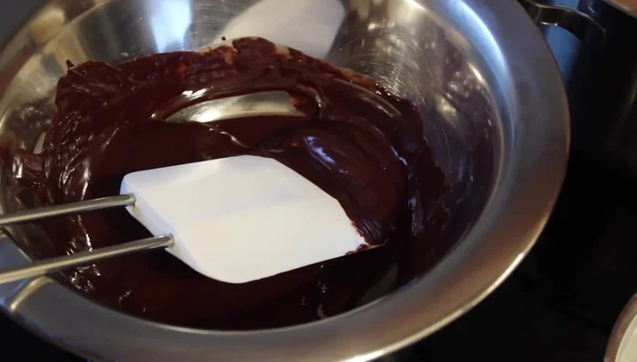 Schokoladensauce zubereiten: Schokolade und Butter im Wasserbad schmelzen, warme Milch hinzufügen und verrühren. (398.139)