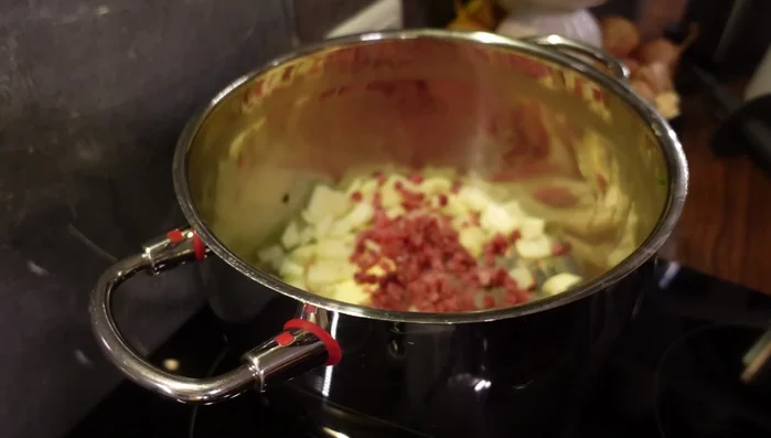 Butter in einem Topf erhitzen, Zwiebeln und Schinkenwürfel darin andünsten (254.28).