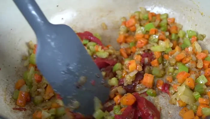 Hummerbasis, Tomatenmark und Knoblauchpaste hinzufügen und verrühren. Alles gut anschwitzen, bis das Gemüse weich und glasig ist.